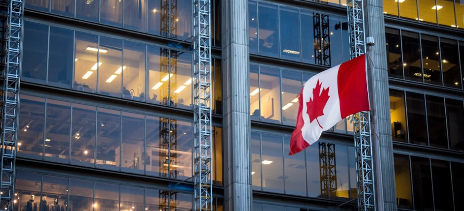 Canadian flag waving in the wind next to an office building