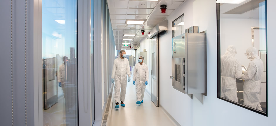 Two CCRM employees walking in a hallway wearing cleanroom suits