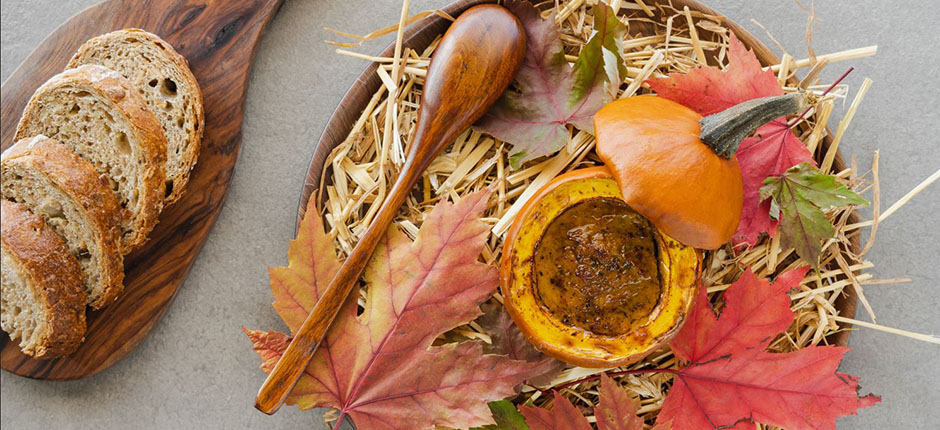 Bread slices and stew in a pumpkin bowl on a festive fall platter.