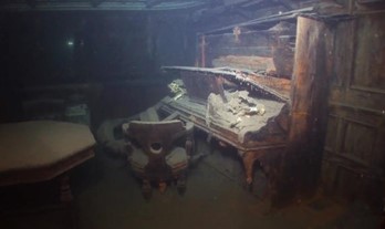 An eroding upright piano seen in the interior of a sunken ship.