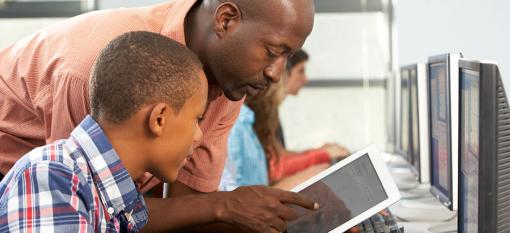 Un instructeur en cybersécurité aide un garçon d'âge scolaire à utiliser une tablette en toute sécurité