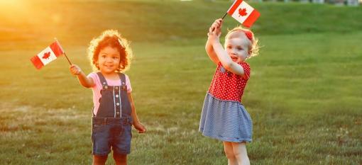 Two children waving small Canadian flags