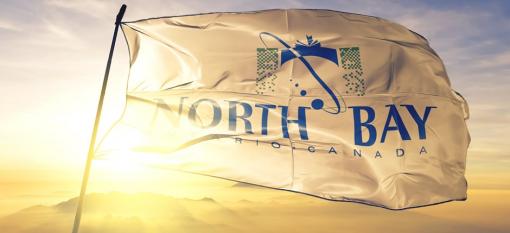 Flag of North Bay, Ontario waving on top of a sunrise