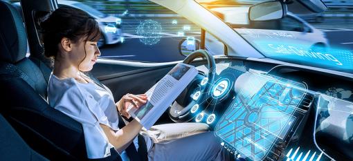 Woman reading while in the driver’s seat of a self-driving vehicle.